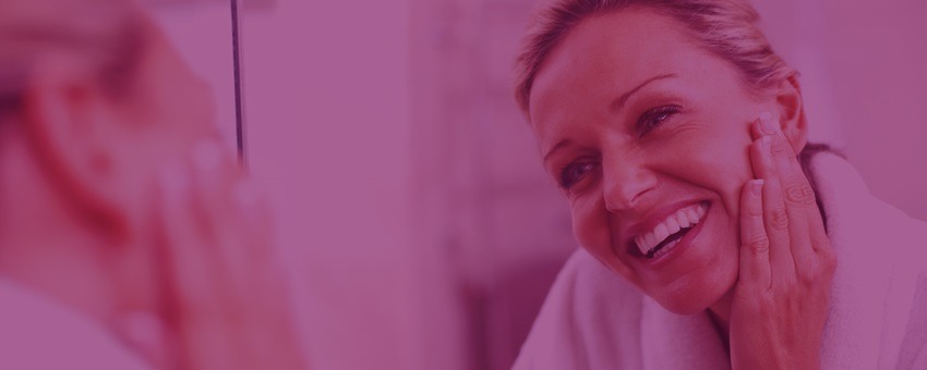 A Woman Smiles Joyfully at Her Reflection in the Mirror, Radiating Confidence and Happiness.